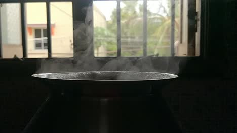 Pot-cooking-rice-in-a-traditional-way-by-boiling-water-in-a-black-background-with-white-smoke-coming-in-slow-motion