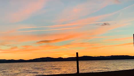 Golden-sunset-time-lapse-at-San-Harbor-beach,-Lake-Tahoe,-NV,-USA-EVENING-CLOUDS-FAST-MOVING-AWAY,-ROLLING-DARK-SUNSET-CLOUDS,-Red-purple-orange-blue-pink-sunset-sky-cloud-time-lapse