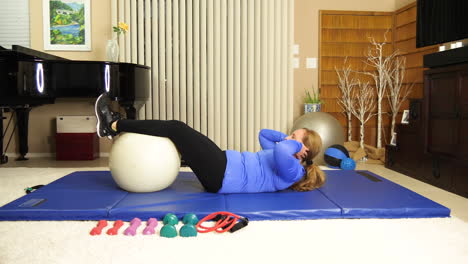 Adult-woman-exercising-at-home-doing-crunches-with-stability-ball-under-her-knees,-portrait,-real-time