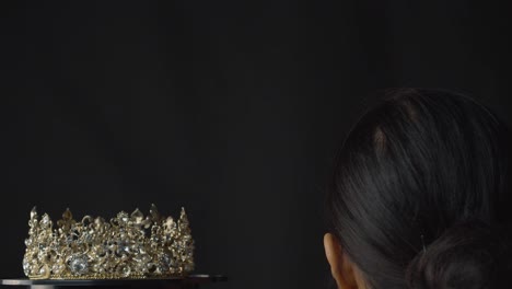 Beauty-pageant-queen-or-bride-places-a-diamond,-pearl-and-silver-crown-on-her-head---black-background
