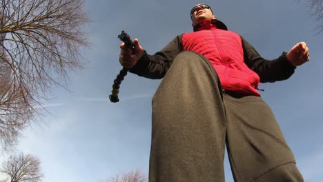 Mid-aged-man-holding-a-gopro-extension-mount-and-skateboarding,-pov-shot
