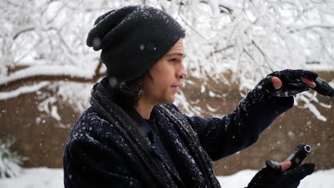 Ein-Kaukasischer-Mann-In-Warmer-Winterkleidung,-Der-In-Zeitlupe-Bei-Kaltem-Wetter-Auf-Sein-Telefon-Blickt