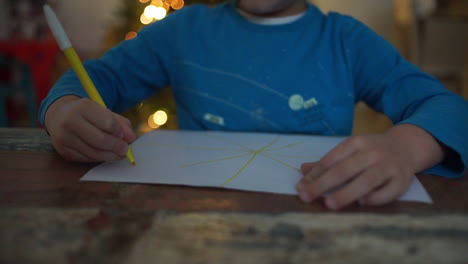 Aufnahmen-Eines-Kindes,-Das-Auf-Papier-Zeichnet,-Mit-Einem-Weihnachtsbaum-Im-Hintergrund