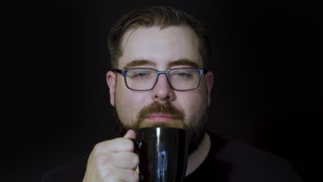 Motion-studio-portrait-of-a-tired,-bearded-man-perking-up-after-enjoying-a-sip-of-coffee