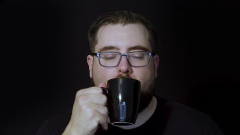 Motion-studio-portrait-of-a-bearded-man-enjoying-a-satisfying-sip-of-coffee