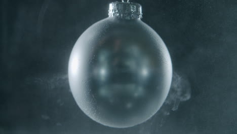 Silver-Christmas-bauble-slowly-spinning-in-a-dark-environment