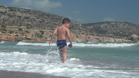 Slow-motion-shot-of-caucasian-boy-toddler,-enjoying-the-sea,-at-beach-of-Varkiza,-Greece