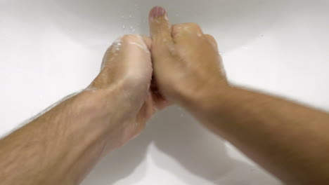 Person's-Hand-Washing-With-Soap-Under-Clean-Tap-Water-From-A-Faucet---High-Angle-Shot