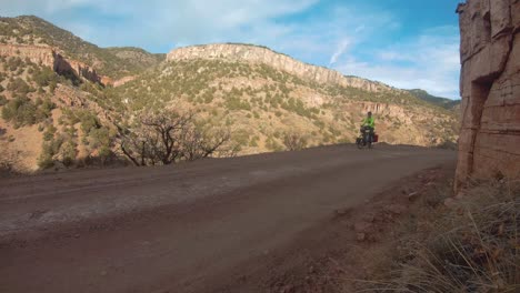 Man-bikepacking-across-Colorado-mountainside-dirt-road,-still-shot