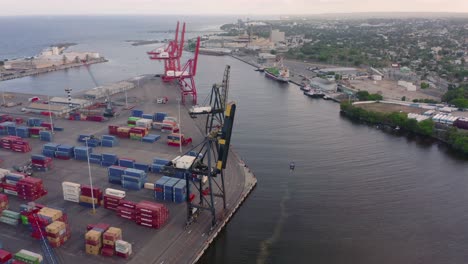 Overhead-scenic-view-of-Puerto-De-Haina-small-port-with-colorful-stacked-cargo-shipping-containers-and-large-cranes,-Dominican-Republic,-above-aerial