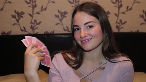 Girl-messing-around-while-playing-cards,-using-cards-as-a-fan