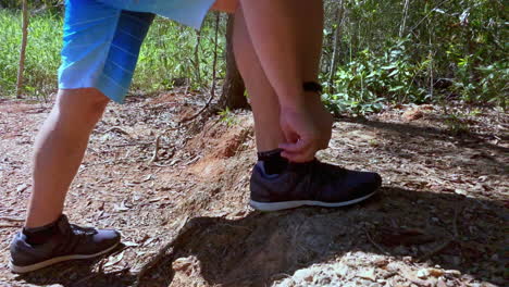 Man-stops-to-tie-his-shoes-whilst-bush-walking