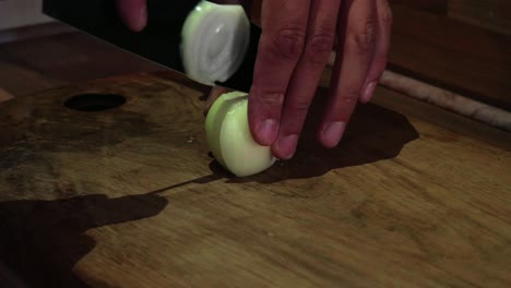 Closeup-shot-of-chef-hands-chopping-onion-on-wooden-cutting-board