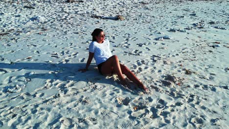 Tourist-Sitting-On-The-White-Sand-Beach-Island-Of-The-Bahamas-Enjoying-The-Bright-Sunlight---Wide-Rolling-Shot