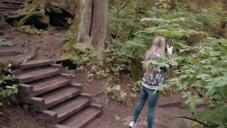 Slow-motion-orbit-shot-of-a-female-photographer-taking-photos-of-the-forest-in-Vancouver-Lynn-valley
