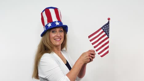 With-a-hat-in-the-star-and-stripes,-a-woman-sways-an-American-flag-in-slow-motion