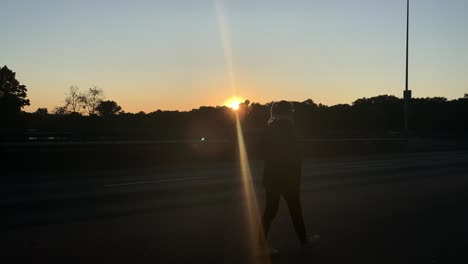 Silhouette-of-blonde-young-pretty-woman-walking-down-the-street-in-front-of-the-sun-going-down