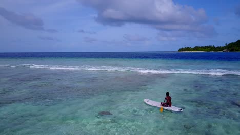 Young-man-exploring-shallow-lagoon-paddling-with-canoe-around-turquoise-waters-close-to-white-waves-coming-from-deep-blue-sea-in-Malaysia