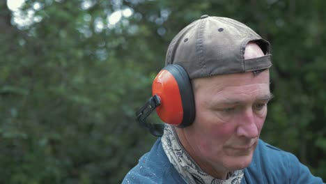 Mature-man-puts-on-safety-equipment-headphones,-visor