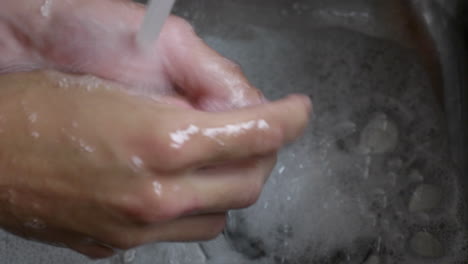 Person's-Hand-Washing-With-Soap-Under-Clean-Tap-Water-From-A-Faucet---To-Prevent-Corona-Virus---High-Angle-Shot