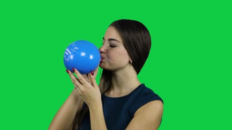 Girl-blowing-up-a-balloon-in-front-of-a-green-screen