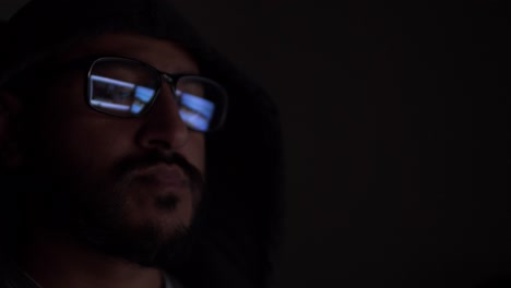 Vermummter-Asiatischer-Mann-Mit-Reflexion-Von-Computerbildschirmen,-Die-In-Einer-Brille-In-Einem-Dunklen-Raum-Zu-Sehen-Sind