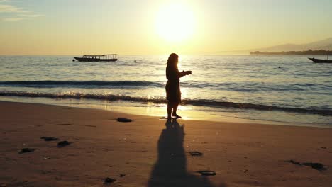 Eine-Frau,-Die-Am-Ufer-Unter-Dem-Schatten-Eines-Glühenden-Sonnenuntergangs-In-Krabi-Beach-Fotografiert---Breite-Aufnahme