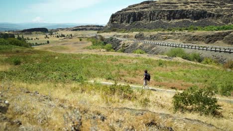 A-lone-mature-woman-day-hiker-walking-along-the-trail-at-Horse-Thief-Butte-State-Park,-Washington