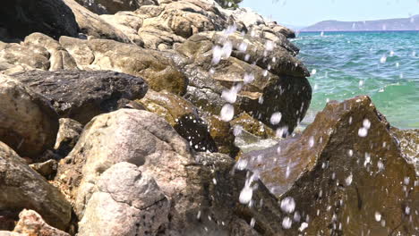 Slow-motion-shot-of-waves-splashing-at-rocks,-Sesi-beach,-Attica-,-Greece