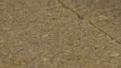 Close-up-of-flapjack-or-granola-cake-mix-getting-sliced-by-an-automated-cutter-on-a-conveyor-system