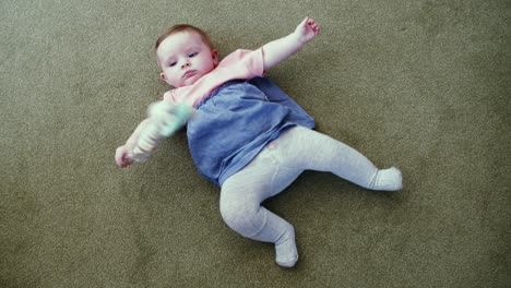 Baby-laying-on-carpet-laughing-and-smiling-playing-with-toy