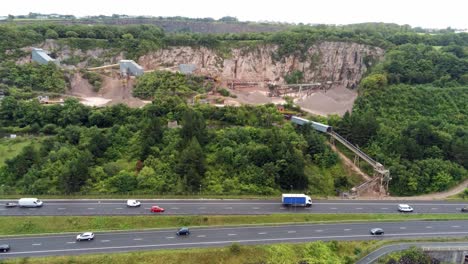 Aerial-rising-above-North-Wales-expressway-to-CEMEX-mining-development-site-on-lush-greenery-hillside