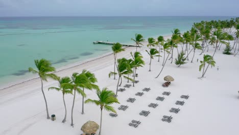 Scenic-summertime-flight-above-empty,-desolate-and-deserted-Juanillo-white-powder-beach-resort-by-turquoise-sandy-beach,-Cap-Cana,-Dominican-Republic,-covid-19-pandemic,-overhead-circle-aerial