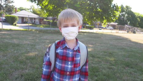 Portrait-of-a-young-boy-in-a-school-field-wearing-a-face-mask