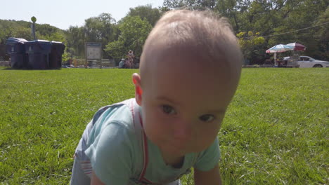 Sweet-baby-boy-crawling-on-the-grass-in-a-park-on-a-sunny-summer-day