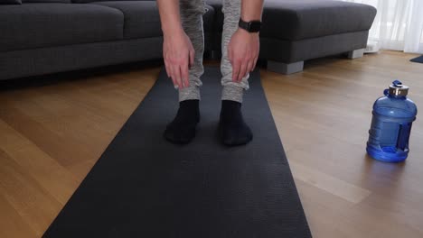Leg-view-of-a-male-athlete-doing-stretching-exercises-on-a-sports-mat-in-the-living-room