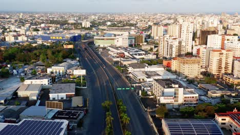 Scenic-aerial-view-of-empty-and-desolate-Kennedy-highway-lanes-in-downtown-Santo-Domingo-on-sunny-day,-Dominican-Republic,-covid-19-pandemic-and-shutdown,-overhead-drone-approach