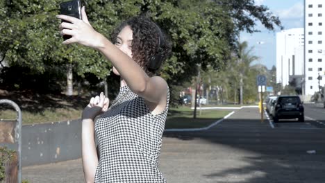 Beautiful-young-lady-with-curly-hair-doing-paused-poses-on-selfie-in-the-square