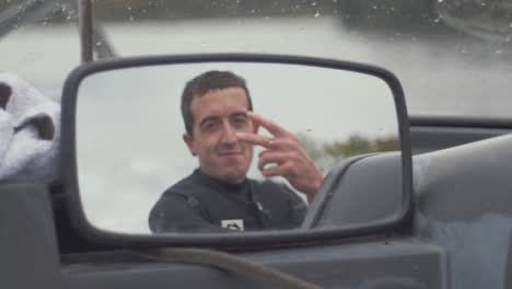 Young-man-looks-in-speedboat-mirror-and-gives-peace-sign