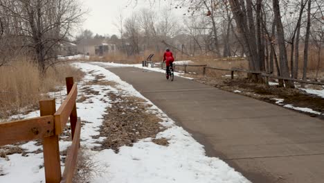An-Der-Kamera-Vorbeirennend-Fährt-Eine-Frau-An-Einem-Kalten-Verschneiten-Tag-Fahrrad