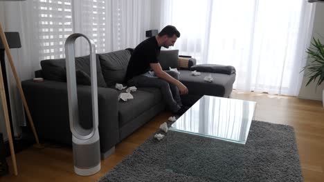 Young-man-on-couch-suffers-from-hay-fever-and-helps-himself-with-an-air-purifier