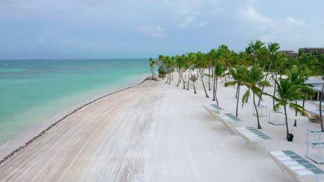 Paradise-scenic-summertime-flight-above-empty,-desolate-and-deserted-Juanillo-white-powder-beach-resort-by-turquoise-sandy-beach,-Cap-Cana,-Dominican-Republic,-covid-19-pandemic,-aerial-approach