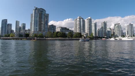 a-pair-bike-surfers,-a-water-taxi-and-a-center-cruiser-motor-boat-passes-by-on-false-creek-yaletown-quay-right-by-the-David-Lam-Park-on-a-summer-day-with-a-reflection-on-the-water-sunny1-3