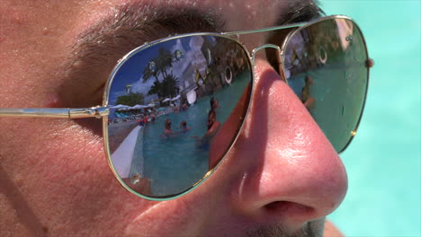 Scene-of-people-in-pool-reflected-in-lens-of-sunglasses
