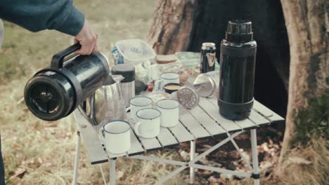 Man-pouring-hot-water-into-tea-pot-camping-on-island