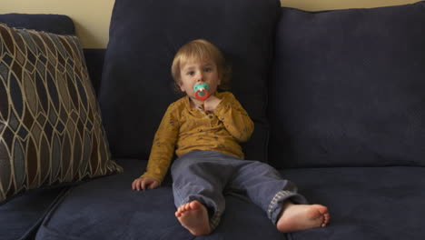 Kleinkindjunge,-Der-Auf-Einem-Sofa-Sitzt-Und-An-Einem-Schnuller-Saugt