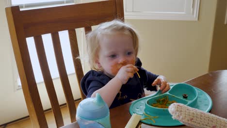 Adorable-toddler-eating-spaghetti-with-her-hands-has-a-messy,-funny-face