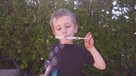 Entzückender-Kleiner-Junge,-Der-An-Einem-Sonnigen-Sommertag-Seifenblasen-Bläst
