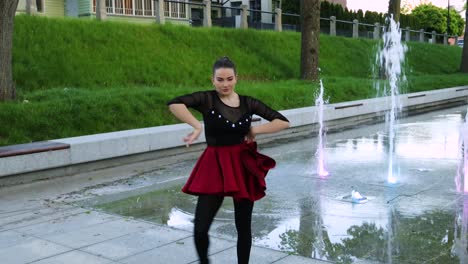 Beautiful-white-female-dancer-dancing-next-to-a-fountain