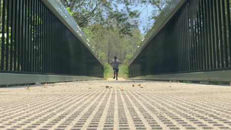 Man-running-on-a-bridge-towards-camera-low-angle-shot